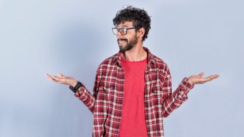 Ein Mann im rotkarierten Hemd und mit Brille, der mit nachdenklicher Miene dasteht und mit beiden Händen gestikuliert, als würde er die Optionen abwägen. Abwägen der Optionen: Ist die Preisgestaltung für Beratungs- und Verwaltungsdienstleistungen in der Vermögensverwaltung fair?