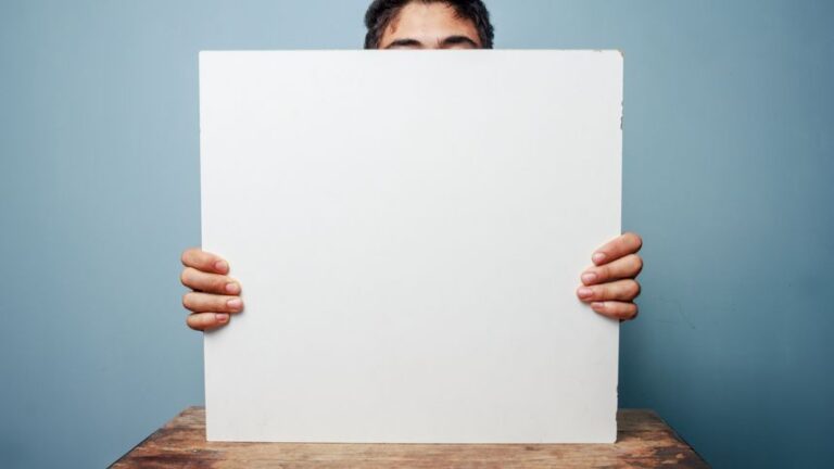 A person holding a blank whiteboard, partially obscuring their face, ready for a presentation.