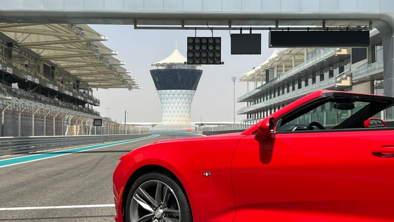 A race car speeding on a track with a wealth manager analyzing financial charts, symbolizing the parallels between racing and wealth management, emphasizing safety and precision.