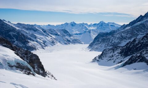 Ein atemberaubendes Luftbild der schneebedeckten Schweizer Alpen, das die Stärke und Stabilität der Schweizer Vermögensverwaltung symbolisiert.