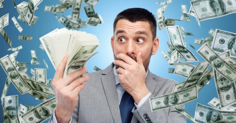 Man in a suit holding stacks of money, surrounded by flying hundred-dollar bills, symbolising the unexpected wealth of Ultra High Net Worth Individuals (UHNWI).