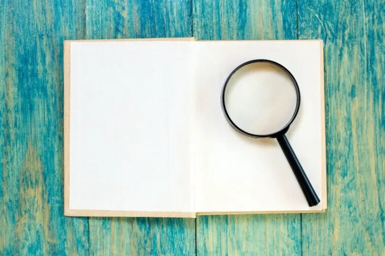 A magnifying glass on an open book, symbolising the search for the best custodian bank for independent wealth managers.