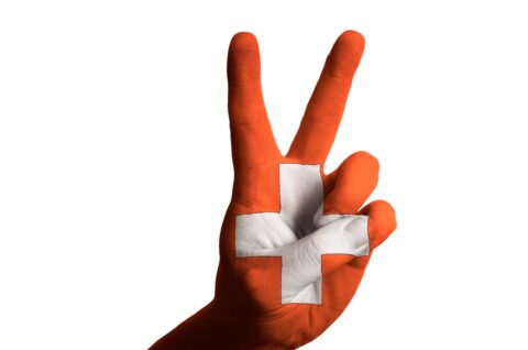 Eine Handbemalung in den Farben der Schweizer Flagge mit einem Friedens- oder Siegeszeichen, das den Umzug in die Schweiz symbolisiert.