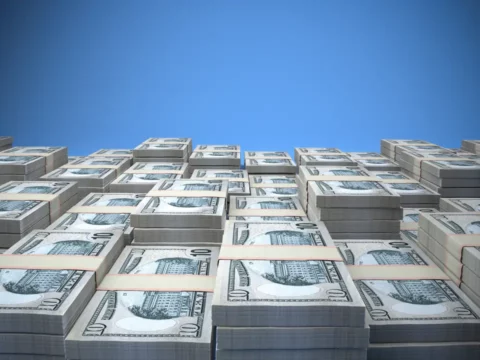 Stapel von 10-Dollar-Scheinen unter einem strahlend blauen Himmel als Symbol für Vermögenserhalt, sichere Investitionen und vermögende Finanzstrategien.