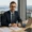 Independent wealth manager in a modern Zurich office with a view of the Swiss Alps and Lake Zurich, reviewing financial documents with a laptop.