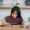 Woman writing at desk surrounded by books — symbolising complexity of KYC documentation