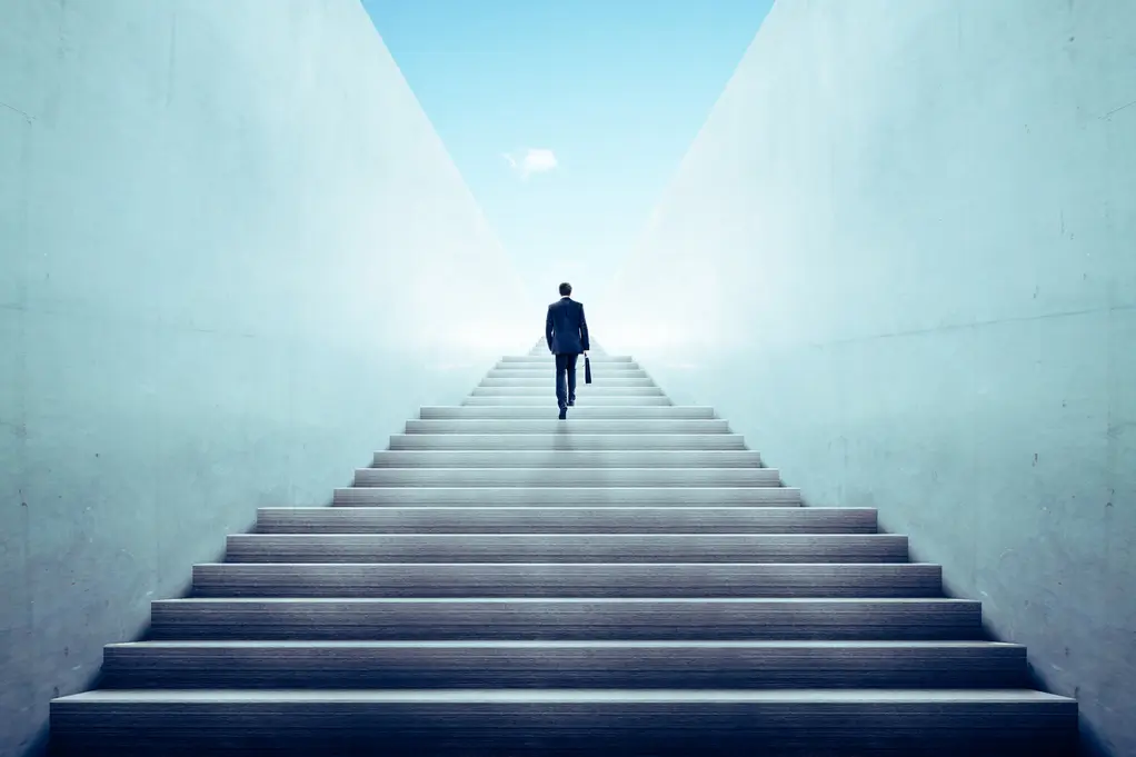 Ein Geschäftsmann, der eine lange Treppe hinaufgeht, symbolisiert den Zinseszinseffekt und das stetige finanzielle Wachstum im Laufe der Zeit.