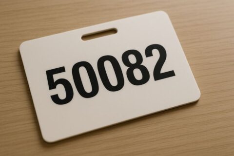 Ausweis eines Privatbankiers mit der Nummer 50082 auf einem Schreibtisch als Symbol für den Mangel an Individualität in großen Instituten