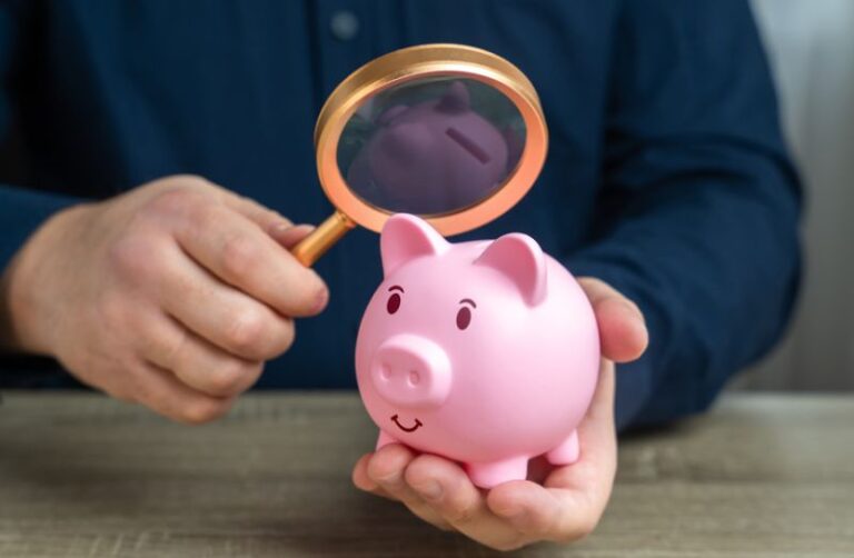 Mit der Lupe inspiziertes Sparschwein zur Veranschaulichung der AML-Risikobewertung