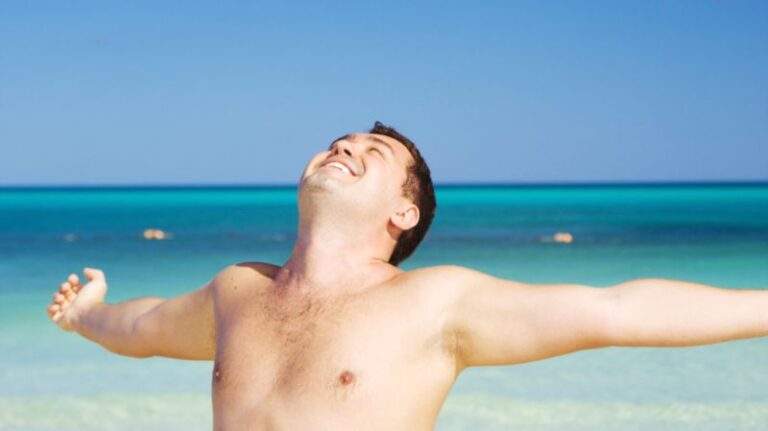 Man enjoying freedom at the beach with open arms symbolising independence and self-discipline.