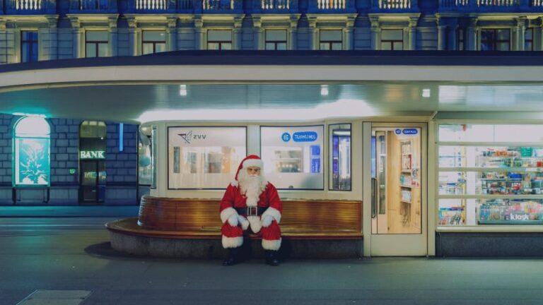 Der Weihnachtsmann sitzt allein auf dem Paradeplatz in Zürich und beobachtet das Finanzviertel während der Weihnachtszeit.