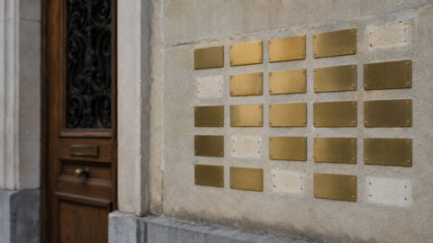 Wall of brass nameplates of Swiss wealth managers beside a building entrance
