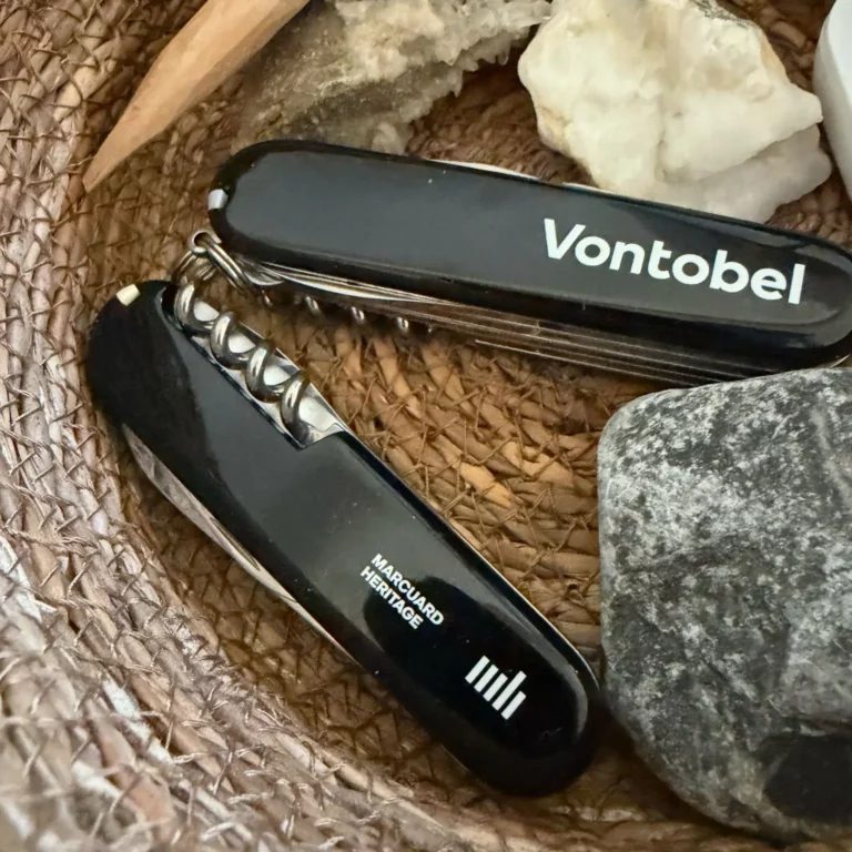 Bank oder unabhängiger Vermögensverwalter: Zwei Schweizer Militärmesser mit unterschiedlichen Logos in einem Korb